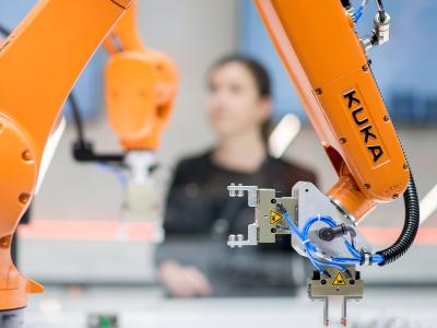 Roboter stehen bei eienr Messe am Stand von Kuka. Kuka