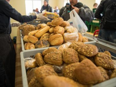 Ehrenamtliche Tafel-Mitarbeiter bei der Verteilung von Brötchen. Tafel