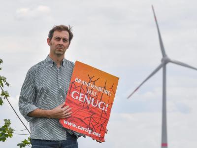 Eigenheimbesitzer Stefan Hellert auf seinem Grundstück. In rund 1500 Metern Entfernung dreht sich der Rotor einer Windenergieanlage. Protest gegen Windkraftanlagen