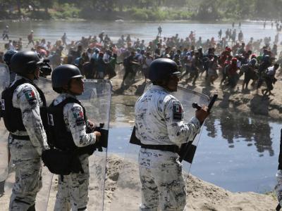 Migranten passieren mexikanischen Nationalgardisten am Grenzfluss Río Suchiate zwischen zwischen Guatemala und Mexiko. Migranten auf dem Weg in die USA