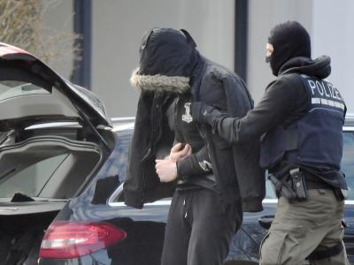Eine Person wird von einem maskierten Polizisten in den Bundesgerichtshof in Karlsruhe gebracht. Festgenommene beim BGH
