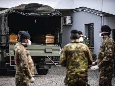 Italienische Soldaten mit Mundschutz vor einem Militärfahrzeug mit Särgen von Corona-Opfern. Särge
