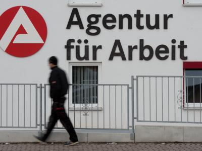 Ein Mann geht an dem Logo der Agentur für Arbeit vorbei. Agentur für Arbeit