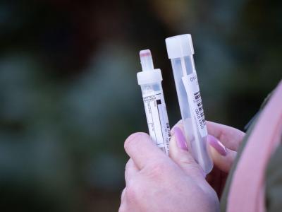 Eine Patientin in Berlin mit zwei Teströhrchen in der Hand für einen Abstrichtest und eine Blutprobe. Warten auf den Test