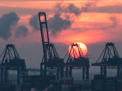 Die Sonne geht im Hafen hinter den Containerbrücken des HHLA Containerterminal Tollerort unter. Hamburger Hafen