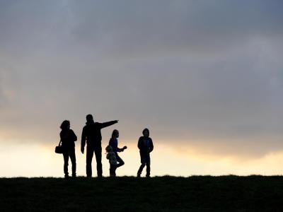 Eine Familie beim Spaziergang unterm abendlichen Wolkenhimmel. Familie