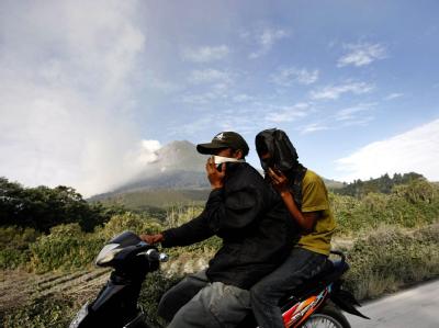 Zwei Indonesier fliehen auf einem Moped vor dem Vulkanausbruch. Der Mount Sinabung war am Sonntag zum ersten Mal seit 400 Jahren ausgebrochen. Flucht vor dem Vulkan